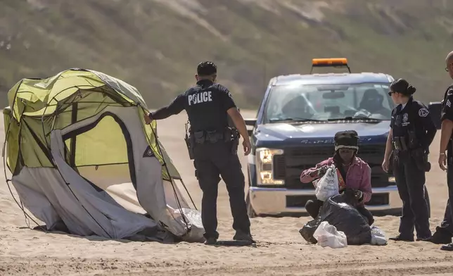 Los Angeles Police pull a tent away as they conduct a cleanup operation to remove homeless encampments at Dockweiler State Beach in Playa del Rey, Los Angeles, on Thursday, Aug. 22, 2024. (AP Photo/Damian Dovarganes)