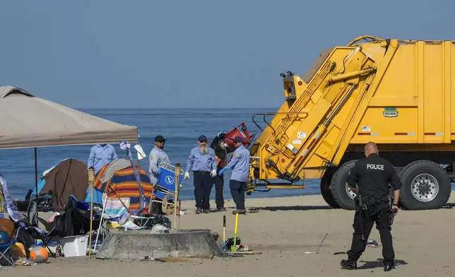 Los Angeles County Department of Beaches and Harbors workers assisted by police conduct a cleanup operation to remove homeless encampments at the Dockweiler State Beach in Playa del Rey, Los Angeles, Thursday, Aug. 22, 2024. (AP Photo/Damian Dovarganes)