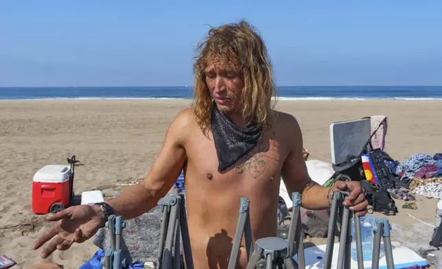 Tyler Eyre, 30, from Salt Lake City, Utah, salvages a few possessions as and beach workers remove his beach camp during a cleanup operation to remove homeless encampments at Dockweiler State Beach in Playa del Rey, Los Angeles, on Thursday, Aug. 22, 2024. (AP Photo/Damian Dovarganes)