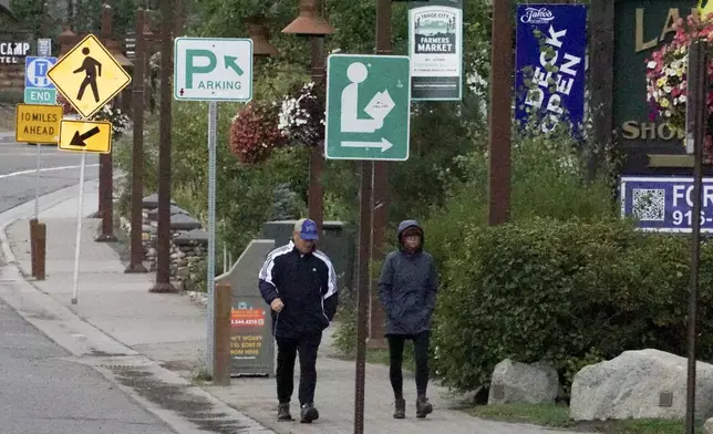 Pedestrians walk in the rain Saturday, Aug. 24, 2024, in Tahoe City, Calif. (AP Photo/Brooke Hess-Homeier)