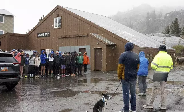 A group of cross country athletes, who had traveled from Davis, Calif., huddle after their practice was canceled due to wet and snowy conditions Saturday, Aug. 24, 2024, in Donner Summit, Calif. (AP Photo/Brooke Hess-Homeier)