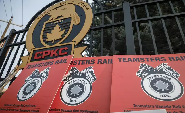 Teamsters Canada Rail Conference picket sign lean up againts a CPKC logo outside the company's headquarters in Calgary, Alta., Friday, Aug. 23, 2024.(Jeff McIntosh /The Canadian Press via AP)