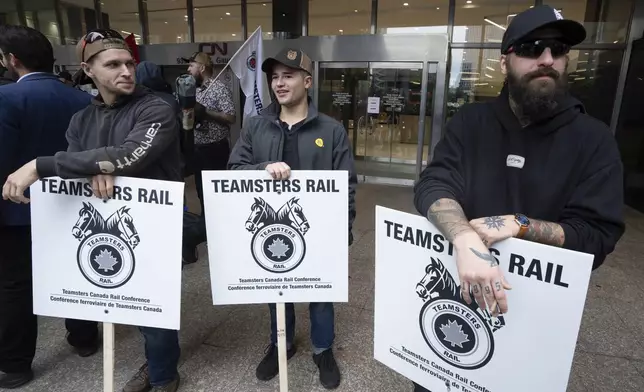 Rail workers picket in front of Canadian National headquarters on the first day of a nationwide rail shutdown, after workers were locked out by Canadian National and CPKC when new contract agreements weren't reached by the midnight deadline, in Montreal, Thursday, Aug. 22, 2024. (Ryan Remiorz /The Canadian Press via AP)