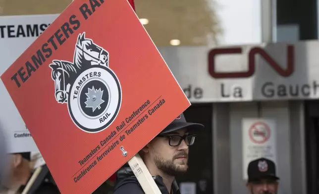 Rail workers picket in front of Canadian National headquarters on the first day of a nationwide rail shutdown, after workers were locked out by CN and CPKC when new contract agreements weren't reached by the midnight deadline, in Montreal, Thursday, Aug. 22, 2024. (Ryan Remiorz /The Canadian Press via AP)