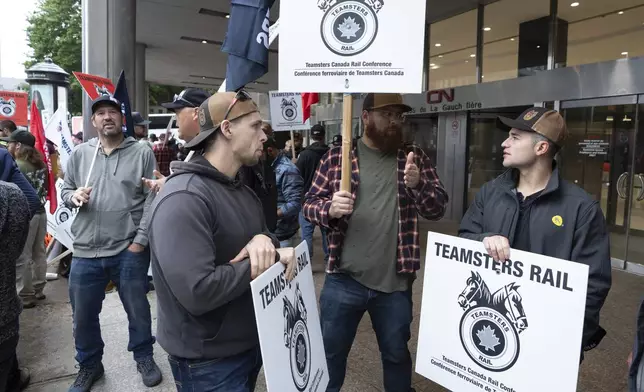 Rail workers picket in front of Canadian National headquarters on the first day of a nationwide rail shutdown, after workers were locked out by CN and CPKC when new contract agreements weren't reached by the midnight deadline, in Montreal, Thursday, Aug. 22, 2024. (Ryan Remiorz /The Canadian Press via AP)