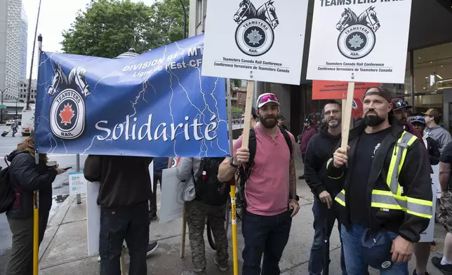 Rail workers picket in front of CN headquarters on the first day of a nationwide rail shutdown, after workers were locked out by CN and CPKC when new contract agreements weren't reached by the midnight deadline, in Montreal, Thursday, Aug. 22, 2024. (Ryan Remiorz/The Canadian Press via AP)