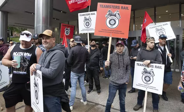 Rail workers picket in front of Canadian National headquarters on the first day of a nationwide rail shutdown, after workers were locked out by CN and CPKC when new contract agreements weren't reached by the midnight deadline, in Montreal, Thursday, Aug. 22, 2024. (Ryan Remiorz /The Canadian Press via AP)