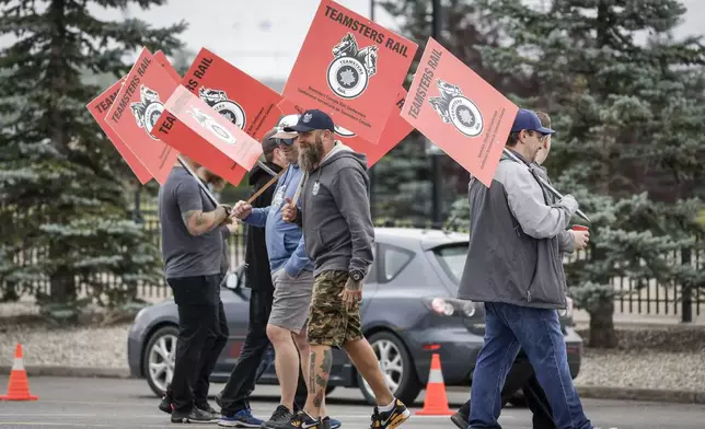 Teamsters Canada Rail Conference members walk a picket line at the CPKC headquarters in Calgary, Alberta, Thursday, Aug. 22, 2024. (Jeff McIntosh/The Canadian Press via AP)