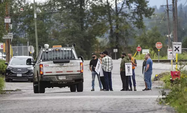 Employees in a pickup truck stop to talk to locked out Canadian National Rail workers standing at a picket line at CN Rail's Thornton Yard in Surrey, British Columbia, Canada, Thursday, Aug. 22, 2024. (Darryl Dyck/The Canadian Press via AP)