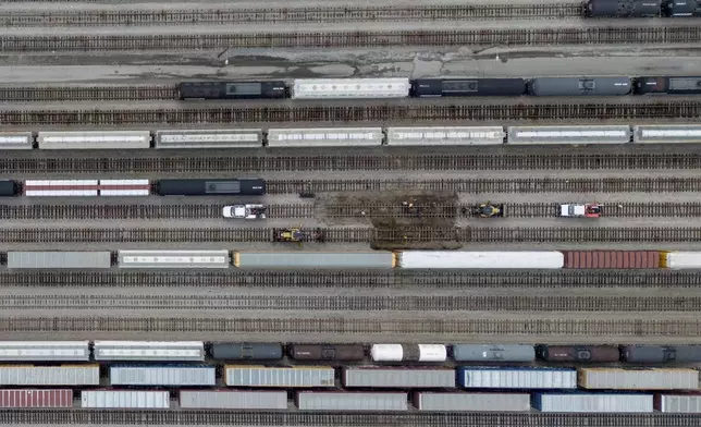 Train cars are seen on the tracks in an aerial view at Canadian National Rail's Thornton Yard as the Port Mann Bridge spans the Fraser River and trucks transport cargo containers on the highway in Surrey, British Columbia, Canada, Thursday, Aug. 22, 2024. (Darryl Dyck/The Canadian Press via AP)