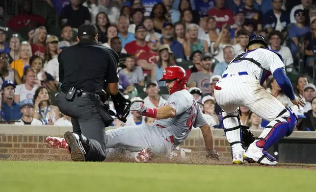 St. Louis Cardinals' Paul Goldschmidt, center, is safe at home plate as Chicago Cubs catcher Miguel Amaya, right, makes a late tag during the seventh inning of a baseball game Thursday, Aug. 1, 2024, in Chicago. (AP Photo/David Banks)