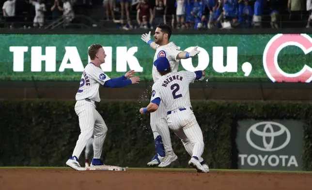 Chicago Cubs pinch hitter Mike Tauchman, top right, celebrates after his walkoff single against the St. Louis Cardinals with Nico Hoerner (2) and Pete Crow-Armstrong, left, during the ninth inning of a baseball game Thursday, Aug. 1, 2024, in Chicago. (AP Photo/David Banks)