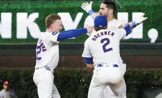 Chicago Cubs pinch hitter Mike Tauchman, top right, celebrates after his walkoff single against the St. Louis Cardinals with Nico Hoerner (2) and Pete Crow-Armstrong, left, during the ninth inning of a baseball game Thursday, Aug. 1, 2024, in Chicago. (AP Photo/David Banks)