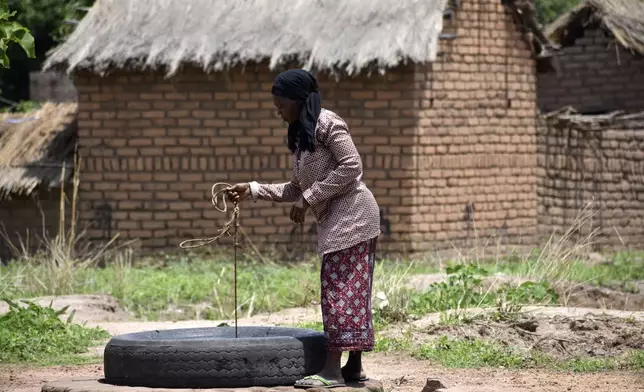 32 year old Marie Depaque, a mother of four children, draws water from a well at the village of Binmar, Chad, Friday, July 19, 2024. (AP Photo/Robert Bociaga)