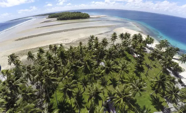 FILE - A section of land between trees is washed away due to rising seas on Nov. 6, 2015, in Majuro Atoll, Marshall Islands. (AP Photo/Rob Griffith, File)