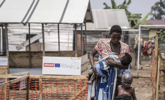 A woman walks with her children suffering from mpox after a treatment at a clinic in Munigi, eastern Congo, Monday, Aug. 19, 2024. Congo will receive the first vaccine doses to address its mpox outbreak next week from the United States, the country's health minister said Monday, days after the World Health Organization declared mpox outbreaks in Africa a global emergency. (AP Photo/Moses Sawasawa)