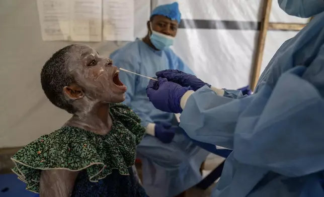 A health worker takes a saliva sample from Lucie Habimana, 13, a mpox patient, at a treatment centre in Munigi, eastern Congo, Friday, Aug. 16, 2024. (AP Photo/Moses Sawasawa)