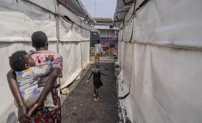 A girl suffering from mpox walks past a treatment centre in Munigi, eastern Congo, Monday, Aug. 19, 2024. Congo will receive the first vaccine doses to address its mpox outbreak next week from the United States, the country's health minister said Monday, days after the World Health Organization declared mpox outbreaks in Africa a global emergency. (AP Photo/Moses Sawasawa)