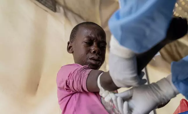 A health worker attends to a mpox patient, at a treatment centre in Munigi, eastern Congo, Monday, Aug. 19, 2024. Congo will receive the first vaccine doses to address its mpox outbreak next week from the United States, the country's health minister said Monday, days after the World Health Organization declared mpox outbreaks in Africa a global emergency. (AP Photo/Moses Sawasawa)