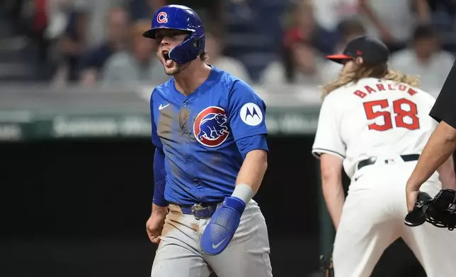 Chicago Cubs' Nico Hoerner, left, shouts near of Cleveland Guardians relief pitcher Scott Barlow (58) after scoring in the seventh inning of a baseball game Monday, Aug. 12, 2024, in Cleveland. (AP Photo/Sue Ogrocki)