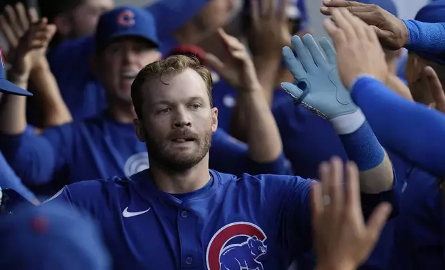 Chicago Cubs' Ian Happ celebrates with teammates in the dugout after hitting a home run in the third inning of a baseball game against the Cleveland Guardians, Monday, Aug. 12, 2024, in Cleveland. (AP Photo/Sue Ogrocki)