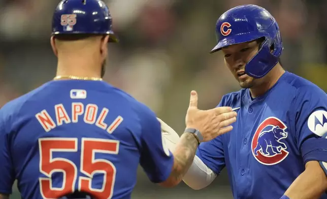 Chicago Cubs' Seiya Suzuki, right, is congratulated by first base coach Mike Napoli (55) in the seventh inning of a baseball game against the Cleveland Guardians, Monday, Aug. 12, 2024, in Cleveland. (AP Photo/Sue Ogrocki)