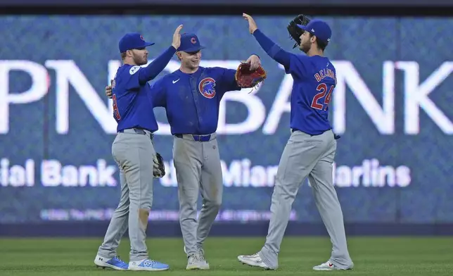 Chicago Cubs outfielders Ian Happ, left, Pete Crow-Armstrong, center and Cody Bellinger celebrate after the Cubs beat the Miami Marlins 6-3, in a baseball game, Friday, Aug. 23, 2024, in Miami. (AP Photo/Wilfredo Lee)