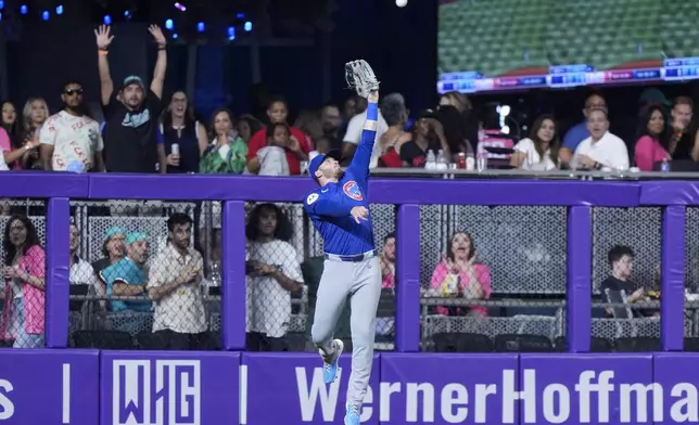 Chicago Cubs left fielder Ian Happ leaps up to catch a ball hit by Miami Marlins' Jesús Sánchez during the first inning of a baseball game, Friday, Aug. 23, 2024, in Miami. (AP Photo/Wilfredo Lee)