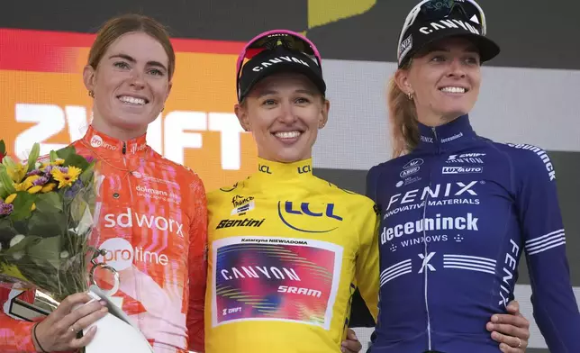 Tour de France Women winner Katarzyna Niewiadoma of Poland, wearing the overall leader's yellow jersey, Demi Vollering of The Netherlands, left and second place, and Pauliena Rooijakkers of The Netherlands, right and third place, celebrate on the podium after the eighth stage of the Tour de France Women cycling race with start in Le Grand-Bornand and finish in Alpe d'Huez, France, Sunday, Aug. 18, 2024. (AP Photo/Peter Dejong)