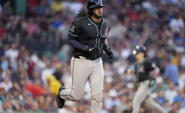 Arizona Diamondbacks' Josh Bell, foreground, draws a walk with the bases loaded that scored Corbin Carroll, back. right, during the first inning of a baseball game against the Boston Red Sox, Friday, Aug. 23, 2024, in Boston. (AP Photo/Michael Dwyer)