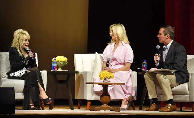 Dolly Parton, left, speaks with Brittany Beshear, center, and Kentucky Governor Andy Beshear to celebrate the expansion of the Imagination Library of Kentucky at the Lyric Theatre in Lexington, Ky., Tuesday, Aug. 27, 2024. The library is now available to all 120 counties of Kentucky and provides books to children up to the age of 5 free books. (AP Photo/Timothy D. Easley)