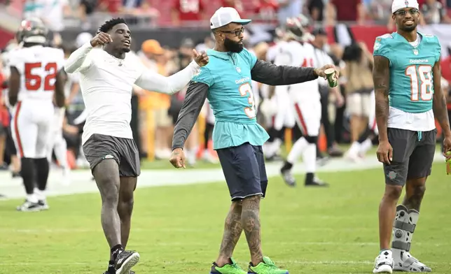 Miami Dolphins wide receivers Tyreek Hill, left, Odell Beckham Jr. (3) and Erik Ezukanma (18) stand of the field before a pre season NFL football game, Friday, Aug. 23, 2024, in Tampa, Fla. (AP Photo/Jason Behnken))