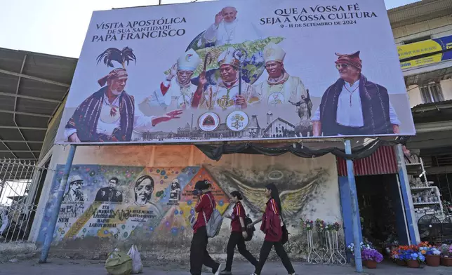 A billboard welcoming Pope Francis stands above a mural honoring Bishop Belo and three others as national heros in Dili, East Timor, Wednesday, Aug. 14, 2024. (AP Photo/Achmad Ibrahim)