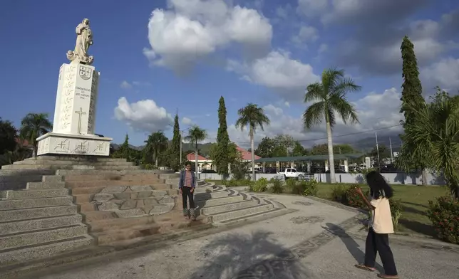 A girl stands for a photograph in front of the Virgin Mary Statue in Dili, East Timor, Tuesday, Aug. 13, 2024. (AP Photo/Achmad Ibrahim)