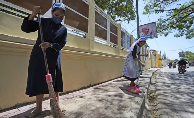 Catholic nuns sweep a sidewalk in Dili, East Timor, Monday, Aug. 12, 2024. (AP Photo/Achmad Ibrahim)