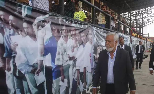 East Timor's Prime Minister and former independence fighter Xanana Gusmao walks past a banner depicting people queuing up to give their votes in the 1999 referendum, during the commemoration of the 25th year anniversary of the country's vote for independence in Dili, East Timor, Friday, Aug. 30, 2024. (AP Photo/Carlos Caro Junior)