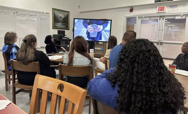 Parents and students in the Lackawanna City School District watch a video demonstrating a new policy that will require the students to lock their cellphones in pouches during the school day, Aug. 19, 2024, in Lackawanna, N.Y. (AP Photo/Carolyn Thompson)