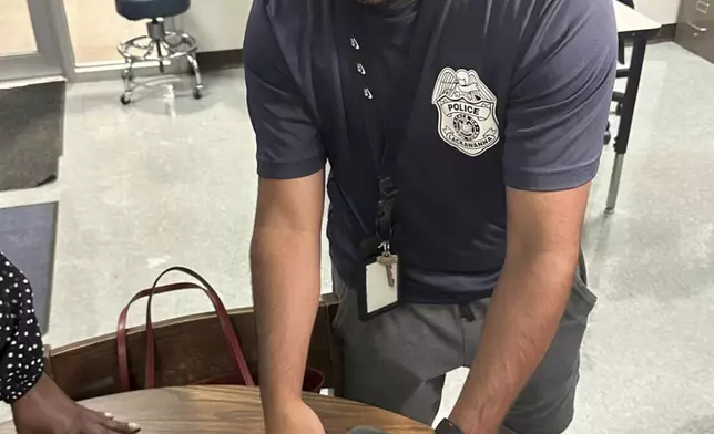 Lackawanna Police Officer Abdul Albaneh, who works with schools, demonstrates how to unlock a cellphone pouch that will prevent students from using their cellphones during the school day to improve student engagement, in Lackawanna, N.Y., Aug. 19, 2024, for when school resumes in September. (AP Photo/Carolyn Thompson)