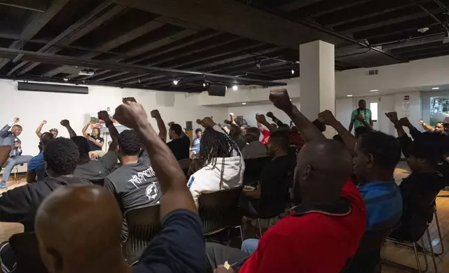 Panelists and attendees raise their fists during a Black Man Lab meeting to discuss the candidacy of Vice President Kamala Harris, Monday, July 22, 2024, in Atlanta. The Black Man Lab hosts weekly gatherings with the purpose of providing an intergenerational safe space for Black men and boys. (AP Photo/Stephanie Scarbrough)