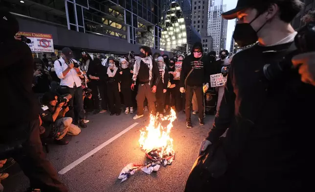 Protesters burn a flag near the Israeli Consulate during the Democratic National Convention Tuesday, Aug. 20, 2024, in Chicago. (AP Photo/Alex Brandon)