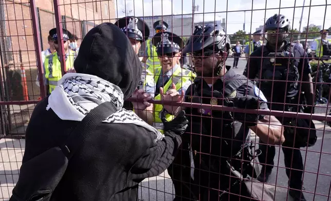 A protester tries to push through a fence surrounding the United Center during the Democratic National Convention Monday, Aug. 19, 2024, in Chicago. (AP Photo/Alex Brandon)