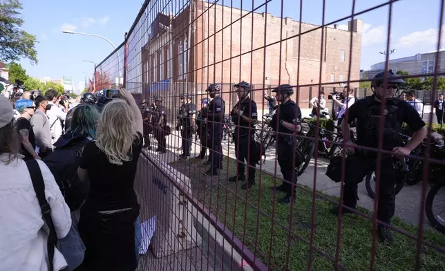 Police walk towards protesters who knock down a fence surrounding United Center at the Democratic National Convention after a march Monday, Aug. 19, 2024, in Chicago. (AP Photo/Alex Brandon)