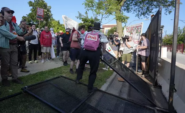 Protesters knock down a fence surrounding United Center at the Democratic National Convention after a march Monday, Aug. 19, 2024, in Chicago. (AP Photo/Frank Franklin II)