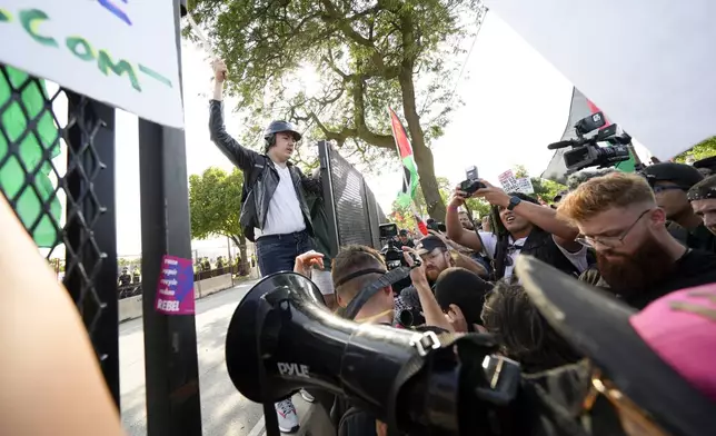 Protesters knock down a fence surrounding United Center at the Democratic National Convention after a march Monday, Aug. 19, 2024, in Chicago. (AP Photo/Julio Cortez)