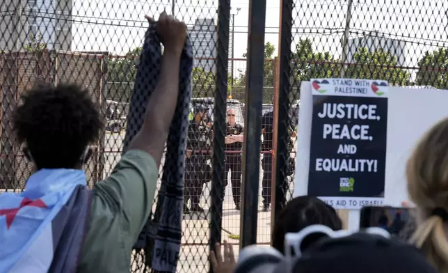 Protesters are stopped by a fence during a march to the Democratic National Convention Monday, Aug. 19, 2024, in Chicago. (AP Photo/Alex Brandon)