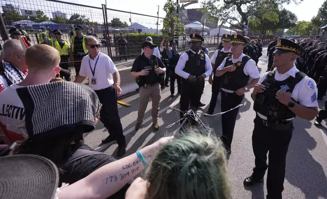 Police walk towards protesters who knock down a fence surrounding United Center at the Democratic National Convention after a march Monday, Aug. 19, 2024, in Chicago. (AP Photo/Alex Brandon)