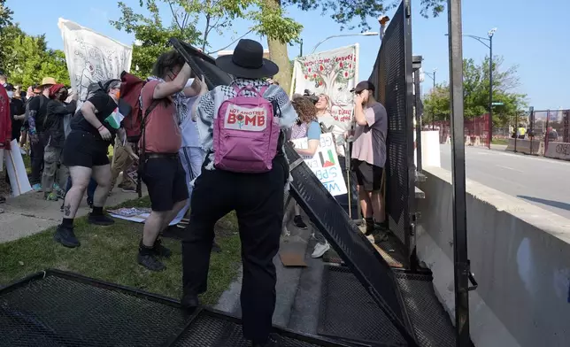 Protesters knock down a fence surrounding United Center at the Democratic National Convention after a march Monday, Aug. 19, 2024, in Chicago. (AP Photo/Frank Franklin II)