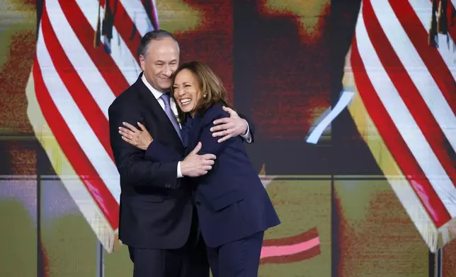 Second gentleman Doug Emhoff, left, hugs Democratic presidential nominee Vice President Kamala Harris during the final day of the Democratic National Convention Thursday, Aug. 22, 2024 in Chicago. (Gabrielle Lurie/San Francisco Chronicle via AP)