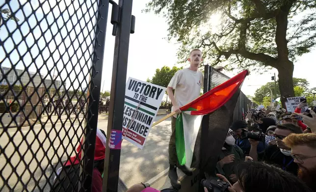 Protesters knock down a fence surrounding United Center at the Democratic National Convention after a march Monday, Aug. 19, 2024, in Chicago. (AP Photo/Julio Cortez)