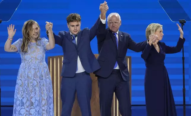 Democratic vice presidential nominee Minnesota Gov. Tim Walz, second from right, poses with his wife Gwen Walz, from right, son Gus Walz and daughter Hope Walz after speaking during the Democratic National Convention Wednesday, Aug. 21, 2024, in Chicago. (AP Photo/J. Scott Applewhite)